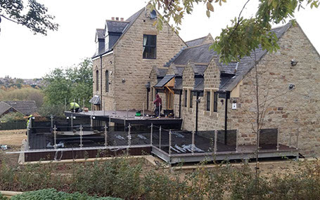 An outside deck with sunken hot tub, walkway & glass hand railing.Designed, supplied & installed by ASH Construction Ltd.